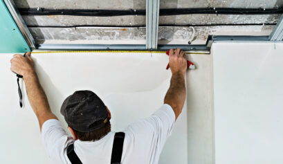 Le travailleur mesure le cadre avant d'installer la cloison sèche. pose d'un faux plafond en plaques de plâtre