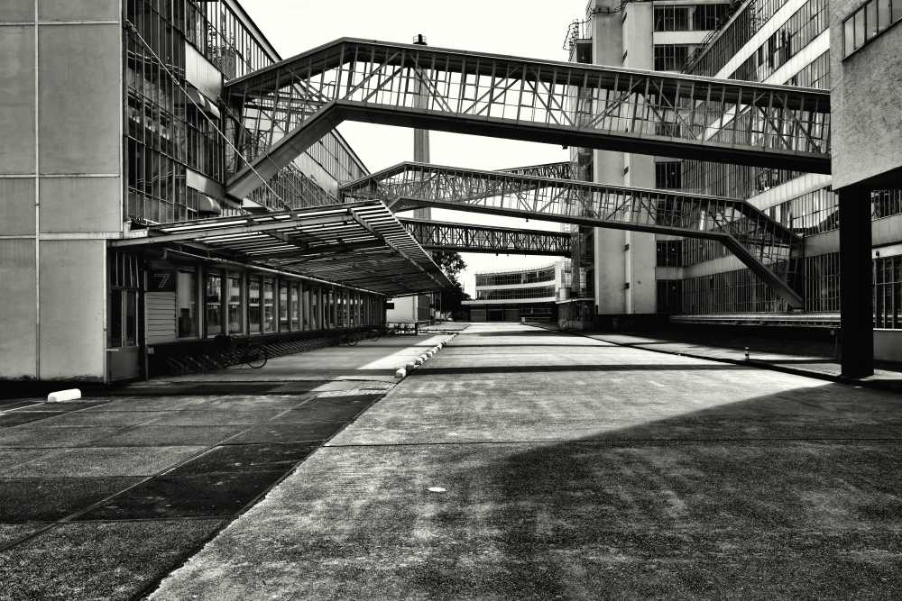 Vue en noir et blanc d’un ancien bâtiment industriel avec passerelles aériennes métalliques reliant les différentes parties de l’usine.