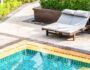 Piscine extérieure avec deux transats sur une terrasse en pierre entourée de végétation